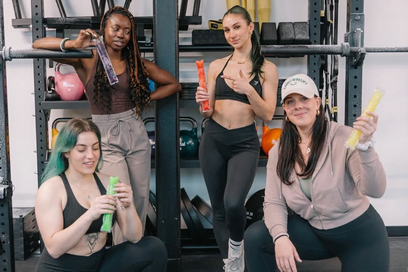 Vier vrouwen in een fitnesszaal, elk met een ijspegel in de hand.